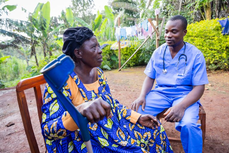A sick old woman explaining her condition to a home visit doctor.