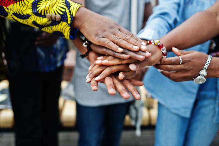 Group of five african college students spending time together on campus at university yard. Black afro friends studying. Education theme. Hands on hands.
