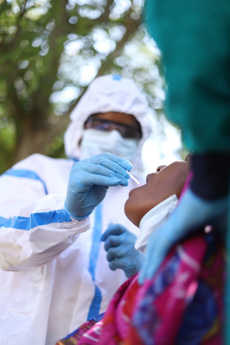 A vertical shot of a healthcare worker taking a coronavirus test from an old Indian woman